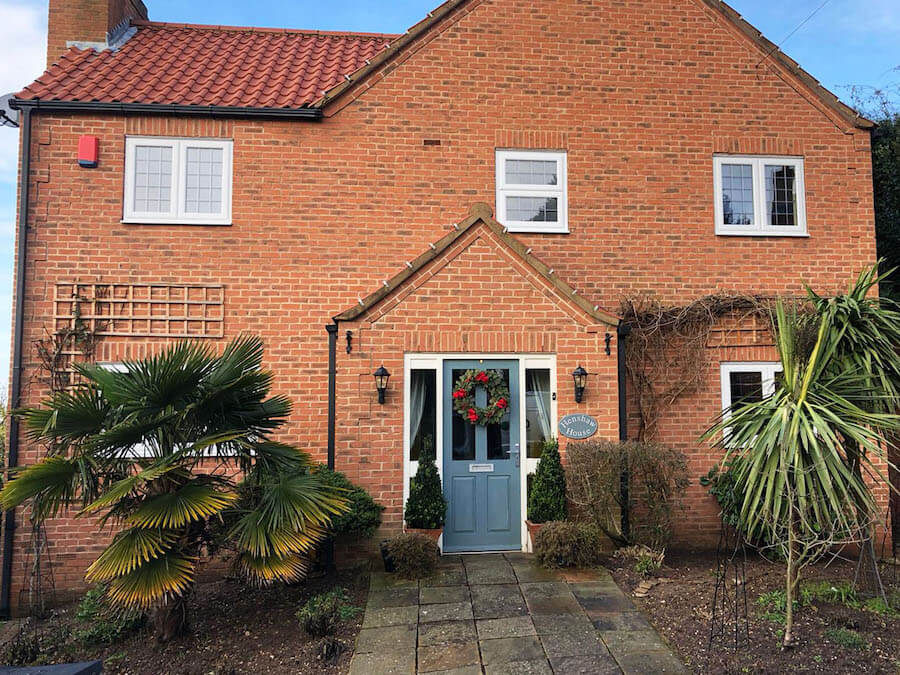 White uPVC casement windows with a light blue door on a large brick house.