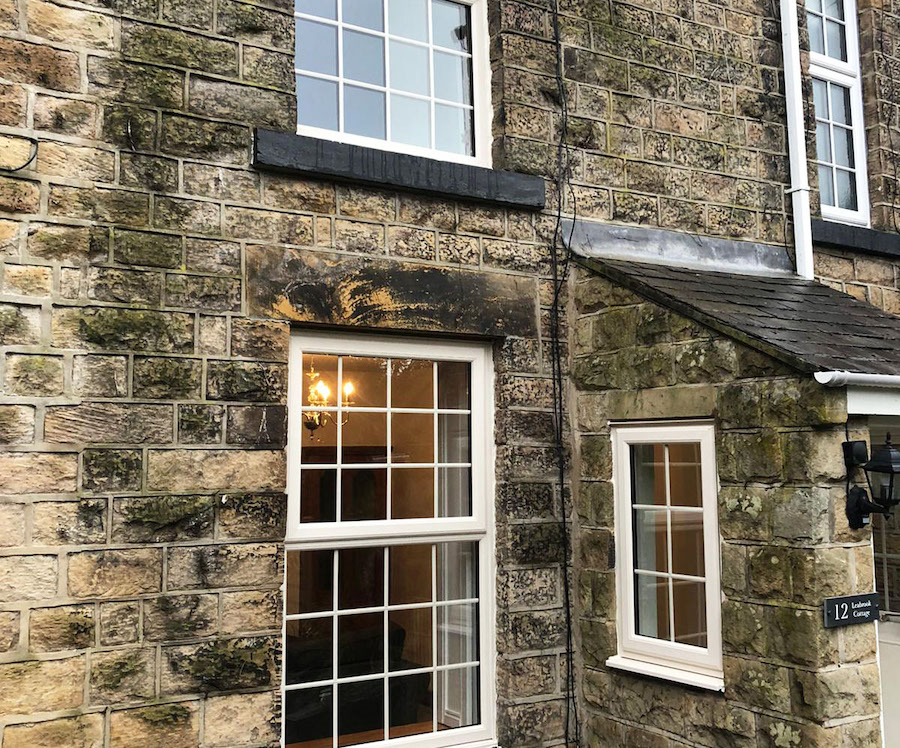 White uPVC casement windows with crossed beads on a stained brick house.