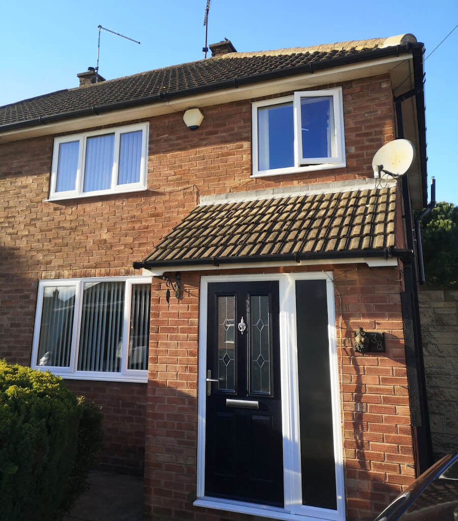 White uPVC casement windows with a black uPVC door above a slate roof.
